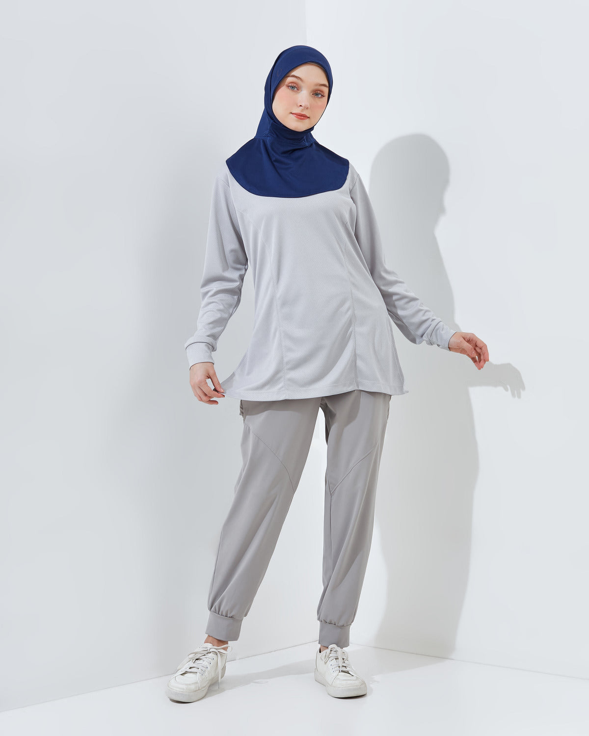 Woman wearing a gray outfit with a blue ONFLD hijab on a white background